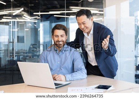 Asian senior boss helping colleague on new employee at workplace inside office, man supports intern, prompts right decisions.