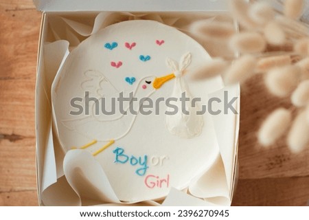Baby shower party cake with white cream cheese frosting decorated with blue and pink boy or girl text. Guess the gender of the upcoming child. He or She cake. Reveal the gender of the unborn baby. Royalty-Free Stock Photo #2396270945