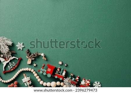Vintage wooden toy Christmas ornaments and garland on green background. Flat lay, top view.