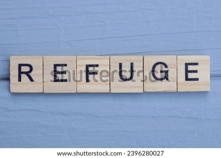 text the word refuge from brown wooden small letters with black font on an gray table