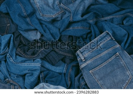 Denim background. Variety of crumpled blue jeans. Top view to stack of jeans denim