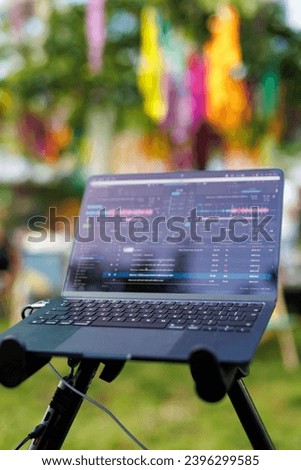A DJ laptop with music editing software in a colorful outdoor festival