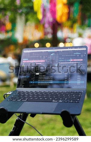 A festive scene of a laptop on a tripod with music software and vibrant decorations in the background