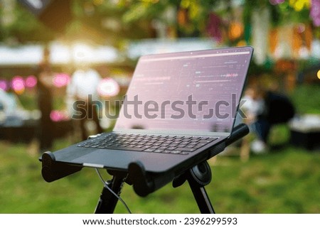 A creative music producer working on a laptop with a colorful garden backdrop