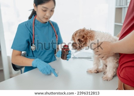Vet is explaining the medication that dog owners must give their dogs when they return home. Dog owner listens to veterinarian explain the medicinal properties of drug used to treat his dog's illness.