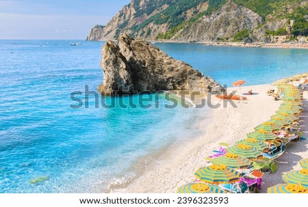 Pebble beach of Monterosso vacation Cinque Terre Monterosso al Mare Chairs and umbrellas fill the Spiaggia di Fegina beach, Monterosso is part of the Cinque Terre Italy. Royalty-Free Stock Photo #2396323593