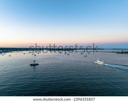 Boat cruising past lighthouse into calm harbor at sunset Black Rock Connecticut Royalty-Free Stock Photo #2396331857