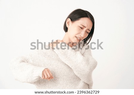 Asian middle aged woman having stiff shoulders in white background Royalty-Free Stock Photo #2396362729