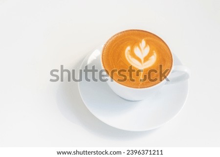 A glass of hot coffee latte with latte art on white table