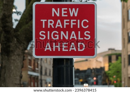 Sign: New traffic signals ahead, with some blurry traffic signals in the background, seen in Ipswich, Suffolk, England, UK