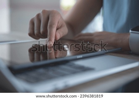 Close up, business woman finger touching on digital tablet and working on laptop computer on office table. Female finger signing on tablet screen, woman student reading Ebook via E-reader mobile app