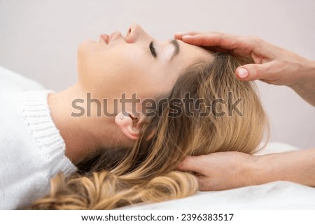 Healer performing set of 32 points of access bars on young woman head, stimulating positive change thoughts and emotions in salon. Alternative medicine concept. High quality photo