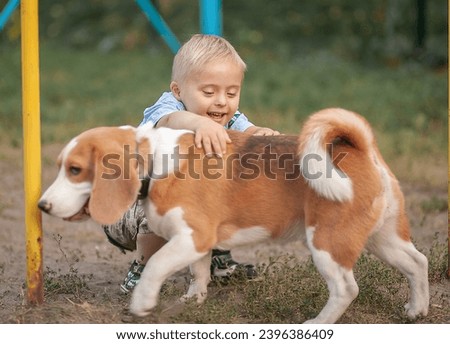 Little cute boy with Down syndrome plays with dogs. Pets and child outside in the park.
