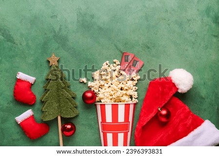 Bucket of popcorn with cinema tickets and Christmas decor on green grunge background
