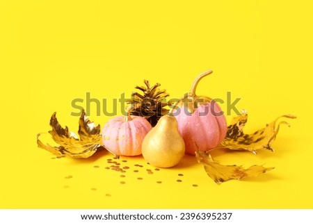 Painted pumpkins with golden pear and leaves on yellow background