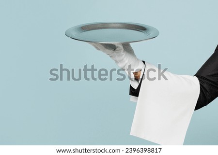 Close up cropped barista male waiter hold in hand plate with empty tray isolated on pastel plain light blue color wall background studio. Restaurant employee concept. Copy space advertising mock up Royalty-Free Stock Photo #2396398817