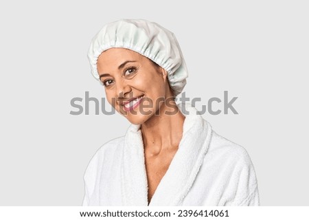 Middle-aged woman in bathrobe with shower cap in studio Royalty-Free Stock Photo #2396414061