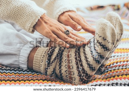 Close up of woman doing stretching exercises on the bed wearing colorful winter warm wool socks. Concept of healthy lifestyle people. Exercises for aged mature female. Touching feet with hands