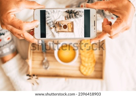 Above view of woman taking food picture of morning breakfast sitting on bed. White copy space of people having photo of coffee and cakes. Christmas holiday leisure activity at home female waking up