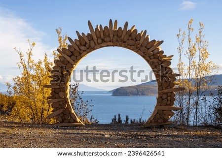 Wooden arch at the observation deck. Sea view. Cape and mountains in the distance. Ecological tourism and nature travel. Ecological trail along the Gertner Bay. Sea of Okhotsk, Magadan region, Russia. Royalty-Free Stock Photo #2396426541