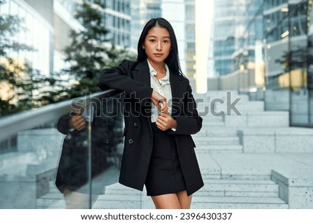 Beautiful Asian business woman in business clothes standing on the steps against the backdrop of business centers.