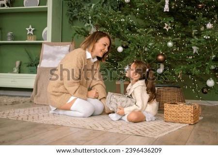 Mom and daughter open Christmas presents early in the morning. Children's happiness to accept gifts in the new year