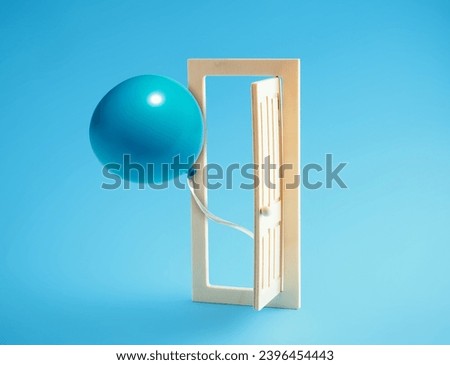 Blue balloon flies out of open wooden door on blue background.