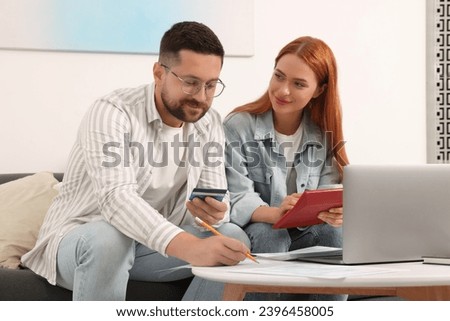 Couple filling in tax payment form at table in living room