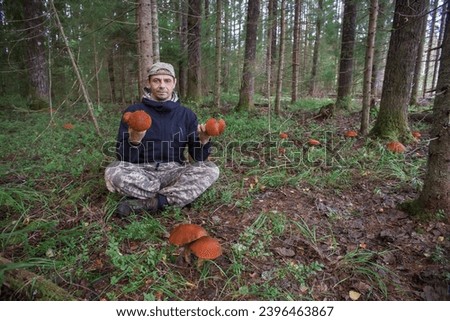 A European man, age 45, sits in a louse on the ground and holds edible mushrooms in his hands. Looks at the camera.