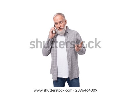 a gray-haired elderly man in a shirt chatting on a mobile phone on a white background with copy space