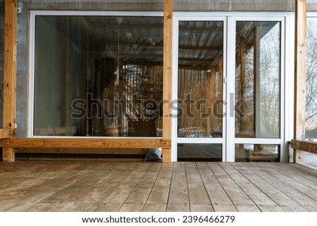 Wooden veranda on the roof of the house. A place in the fresh air to relax or practice yoga, meditation. Construction of a loft-style balcony. Panoramic windows and glass doors. coffee shop concept