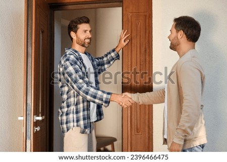 Friendly relationship with neighbours. Happy men shaking hands near house outdoors Royalty-Free Stock Photo #2396466475