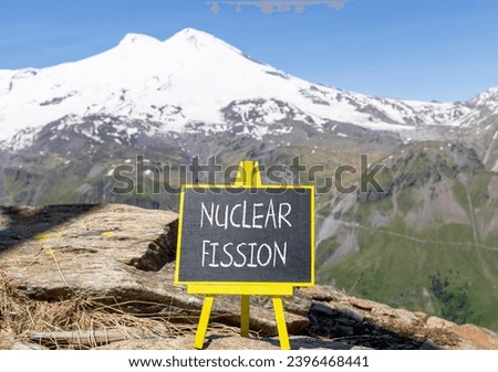 Nuclear fission symbol. Concept words Nuclear fission on beautiful black chalk blackboard. Chalkboard. Beautiful mountain Elbrus background. Business science nuclear fission concept. Copy space. Royalty-Free Stock Photo #2396468441