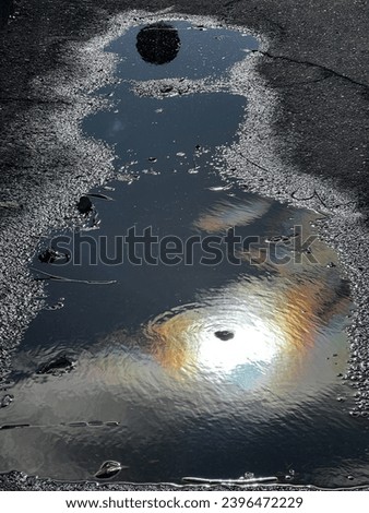 Abstract photo of the sun's rays reflected in a puddle Royalty-Free Stock Photo #2396472229