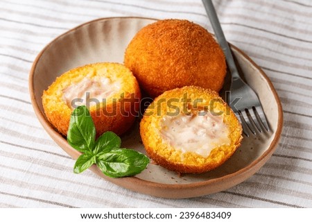 Arancini are Italian rice balls that are stuffed, filled with ham prosciutto and mozzarella, coated with breadcrumbs and deep fried.  Sicilian snack, street food.  Royalty-Free Stock Photo #2396483409