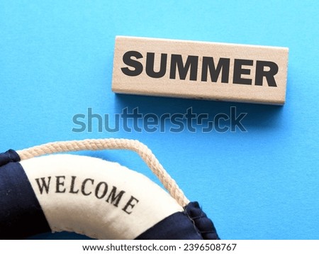 word SUMMER on wooden block and blue background.