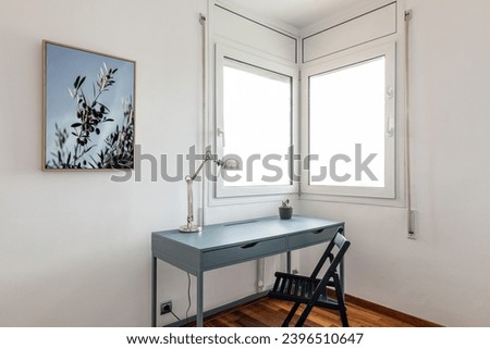 Desk with lamp and chair by corner windows in apartment