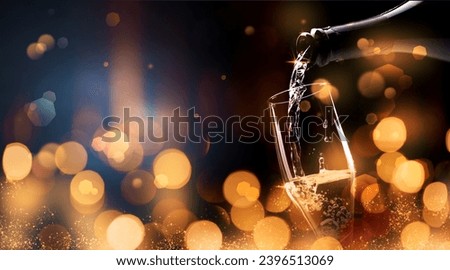 Happy New Year celebration banner with golden bokeh light and sparkling wine pouring in a glass, copy space