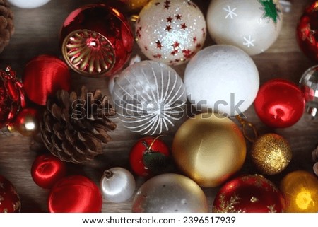 Pine cones and red, golden and white Christmas ornaments on wooden background. Selective focus.