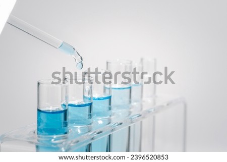 Chemistry laboratory tube glass, science laboratory research and development concept, flask, beaker, and test tubes with dropping blue liquid water sample test, scientific test tubes equipment. Royalty-Free Stock Photo #2396520853
