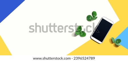 White smartphone with shamrock leaves - flat lay