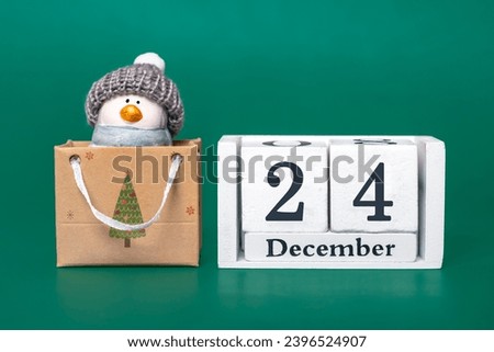 Christmas penguin in hat on  wooden calendar date 24 December isolated on green background Concept of Merry Christmas preparation, xmas atmosphere Wishes card