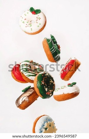 

3D image Flying Christmas donuts. Colorful doughnuts with sprinkles falling or flying in motion against white background. Selective focus