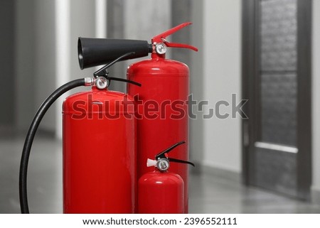 Three red fire extinguishers in hall. Space for text Royalty-Free Stock Photo #2396552111