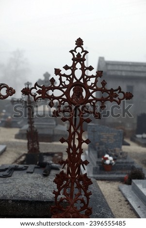 Exterior photo view of a foggy scary cemetery with many christians tombstones, graveyards, tombs, crosses during a misty foggy fog dark day with a grey gray humid weather in winter