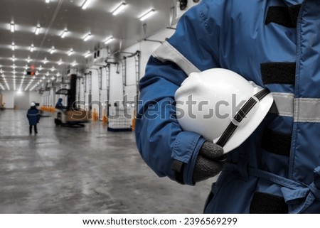 Officer holding hardhat for dangerous accident protection in warehouse during work. Cold room storage and freezing warehouse. Cold Storage Room Service, Inventory Management Concept. Royalty-Free Stock Photo #2396569299