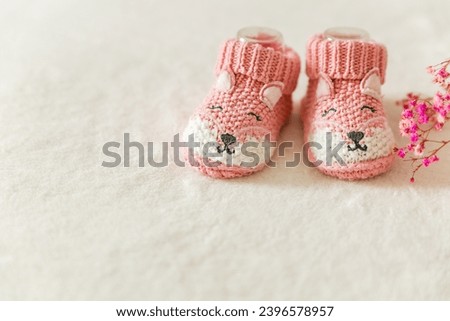 Pink knitted baby socks, booties on a white background with copy space. Pregnancy and motherhood concept, first birthday banner, handmade socks, baby warm clothes, handmade knitted socks, hobby. Royalty-Free Stock Photo #2396578957