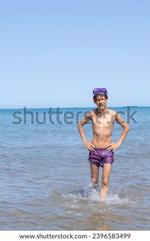 Handsome teen grins with a diving mask, embracing the beach's playful atmosphere on a warm and sunny day,vertical photo. Royalty-Free Stock Photo #2396583499