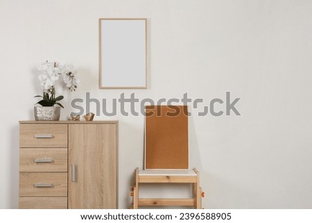Chest of drawers, table, orchid and picture frames indoors, space for text. Interior design