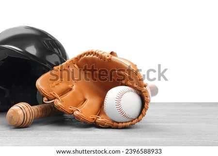 Baseball glove, bat, ball and batting helmet on light grey wooden table against white background